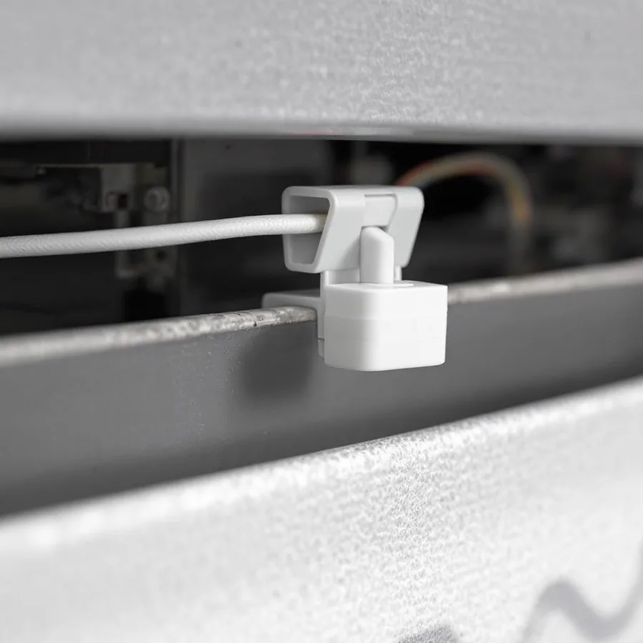 Small white plastic float safety switch clipped to the rim of a condensate drain pan with a thin wire leading from it