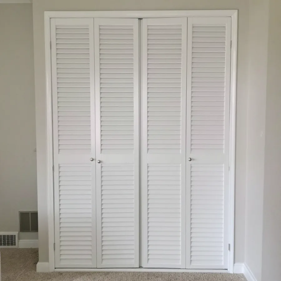 Closed white louvered bifold closet door in a residential hallway with a small floor register beside it