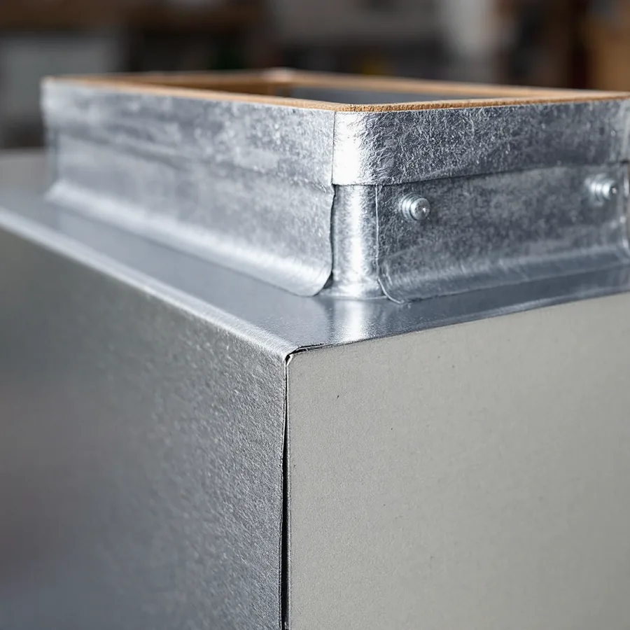 Top of a plain sheet metal cabinet where a rectangular galvanised supply plenum attaches