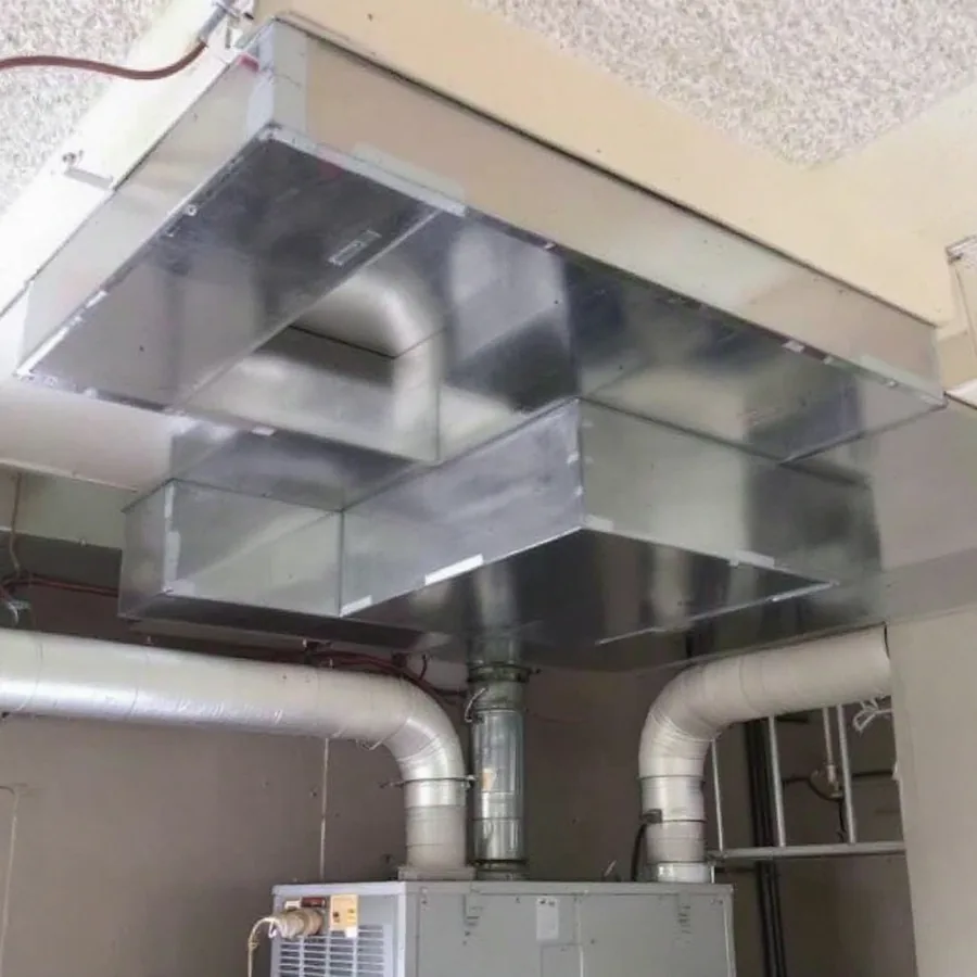 Rectangular sheet metal supply and return plenums above an indoor air handler with taped joints and branch ducts leaving the sides