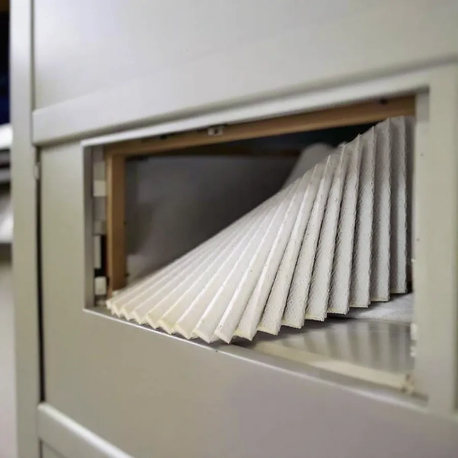 Clean pleated air filter half inserted into the filter slot of an indoor air handler cabinet